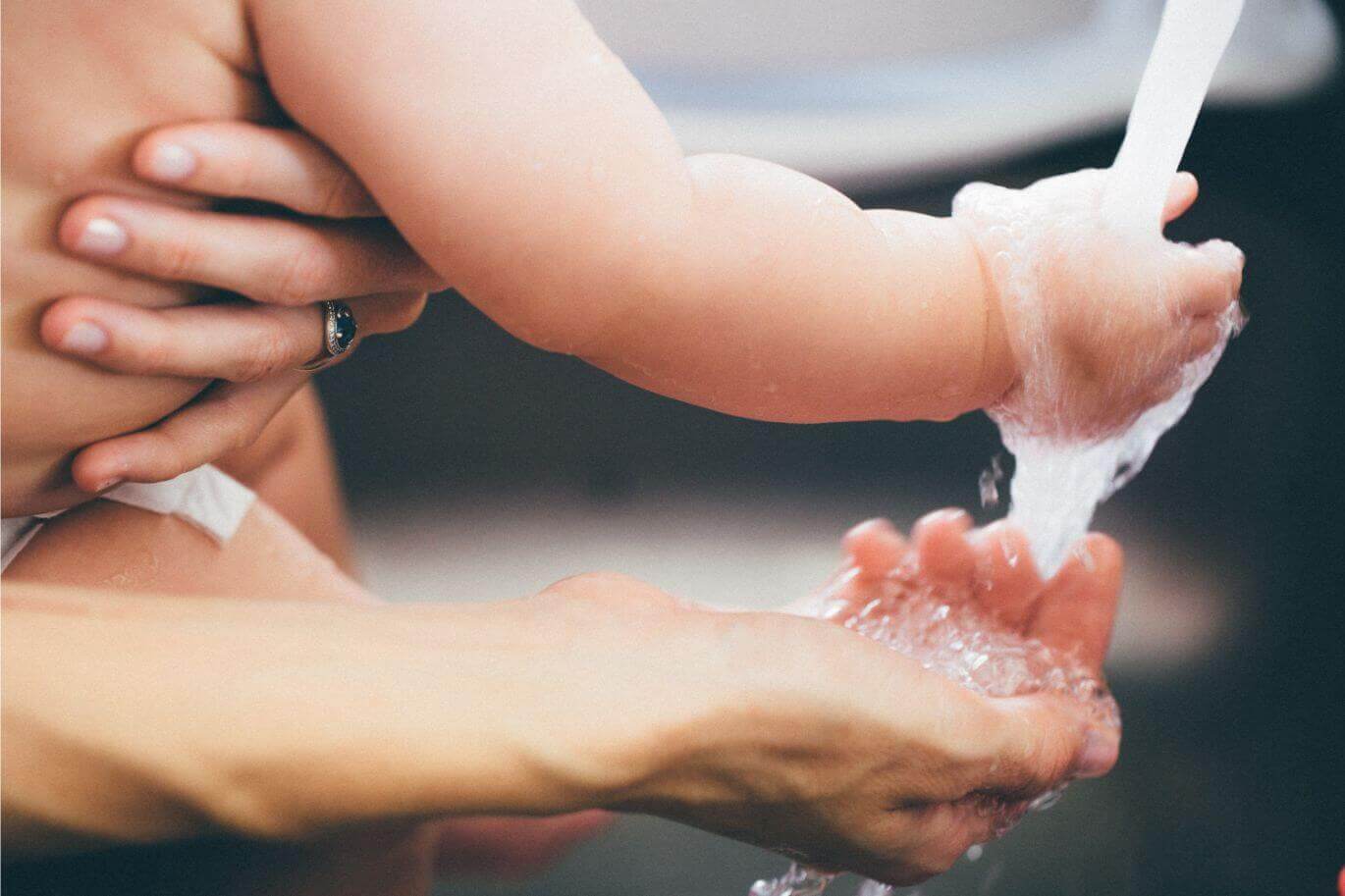 baby and mother with their hands on the water