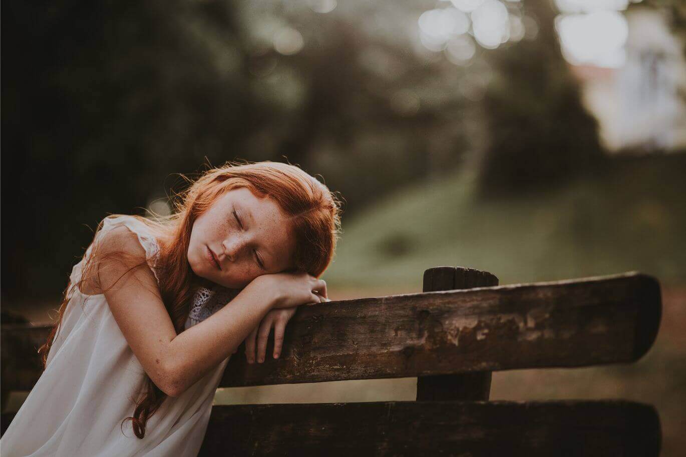 ginger girl sleeping in a chair in the middle of a park